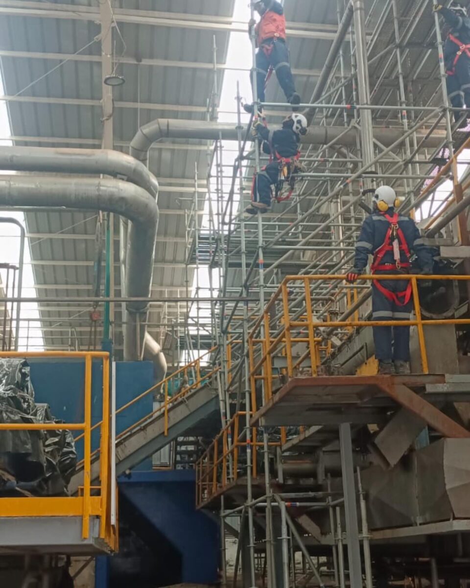 Montador con arnés trabajando en andamio industrial